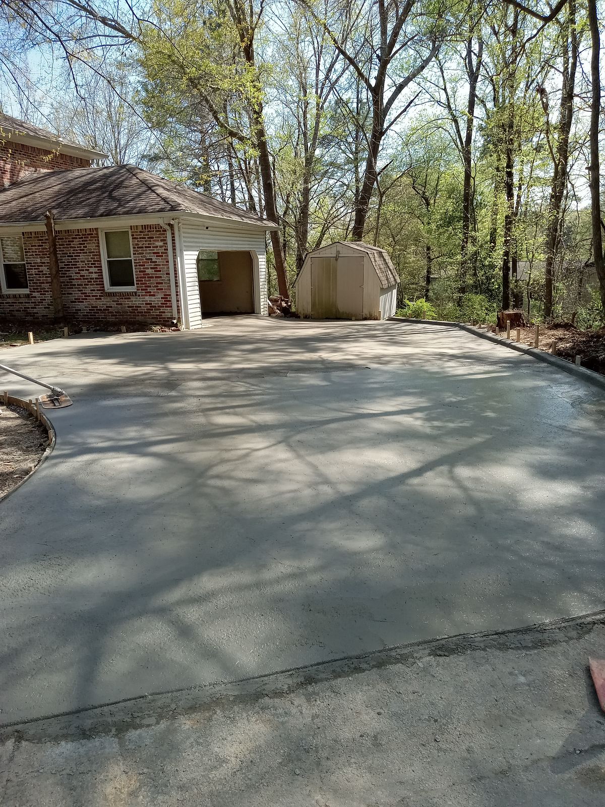 Freshly poured residential concrete driveway in front of a brick home